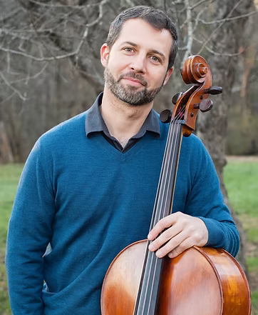 A photo of Avi Friedlander posing with his cello outside.